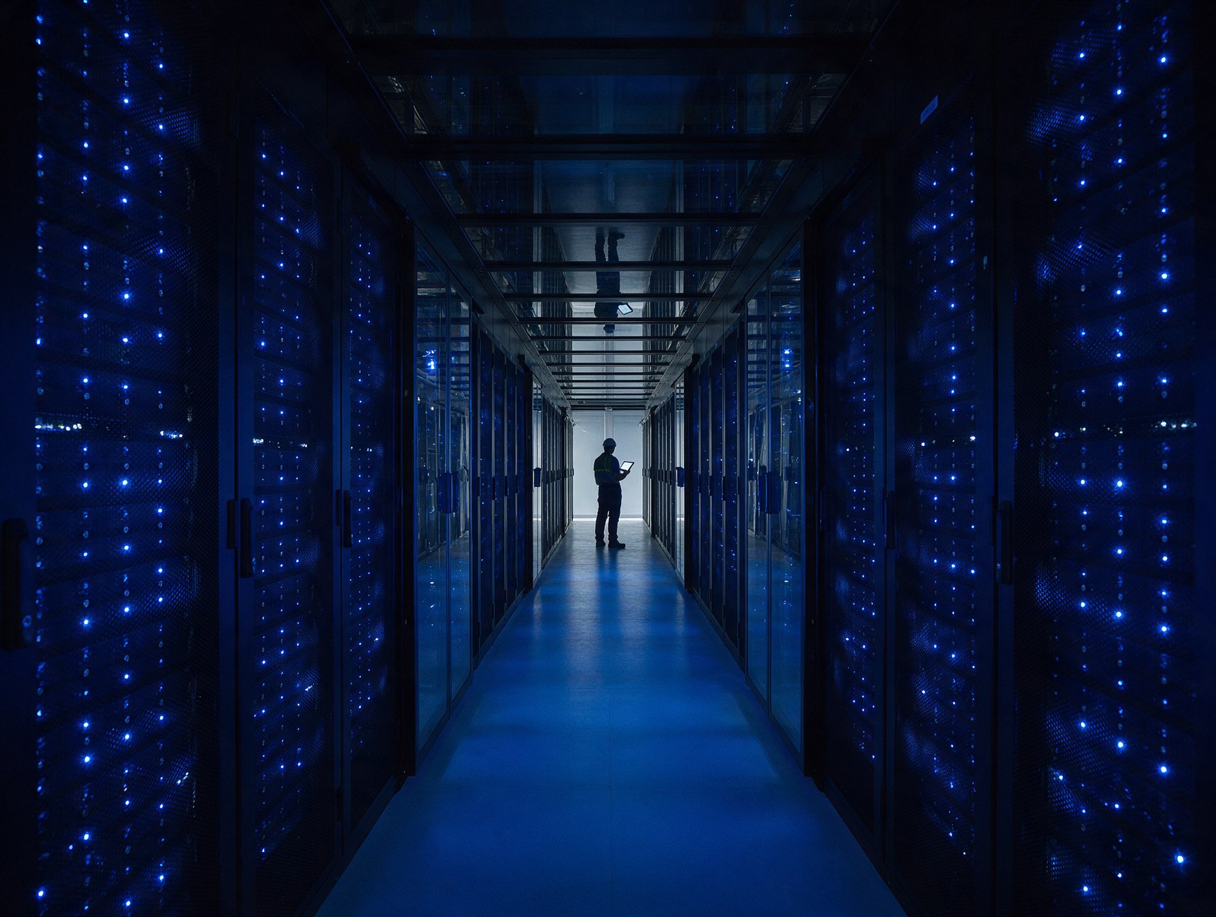Completed data hall with lit cabinets and an engineer at the end of the aisle