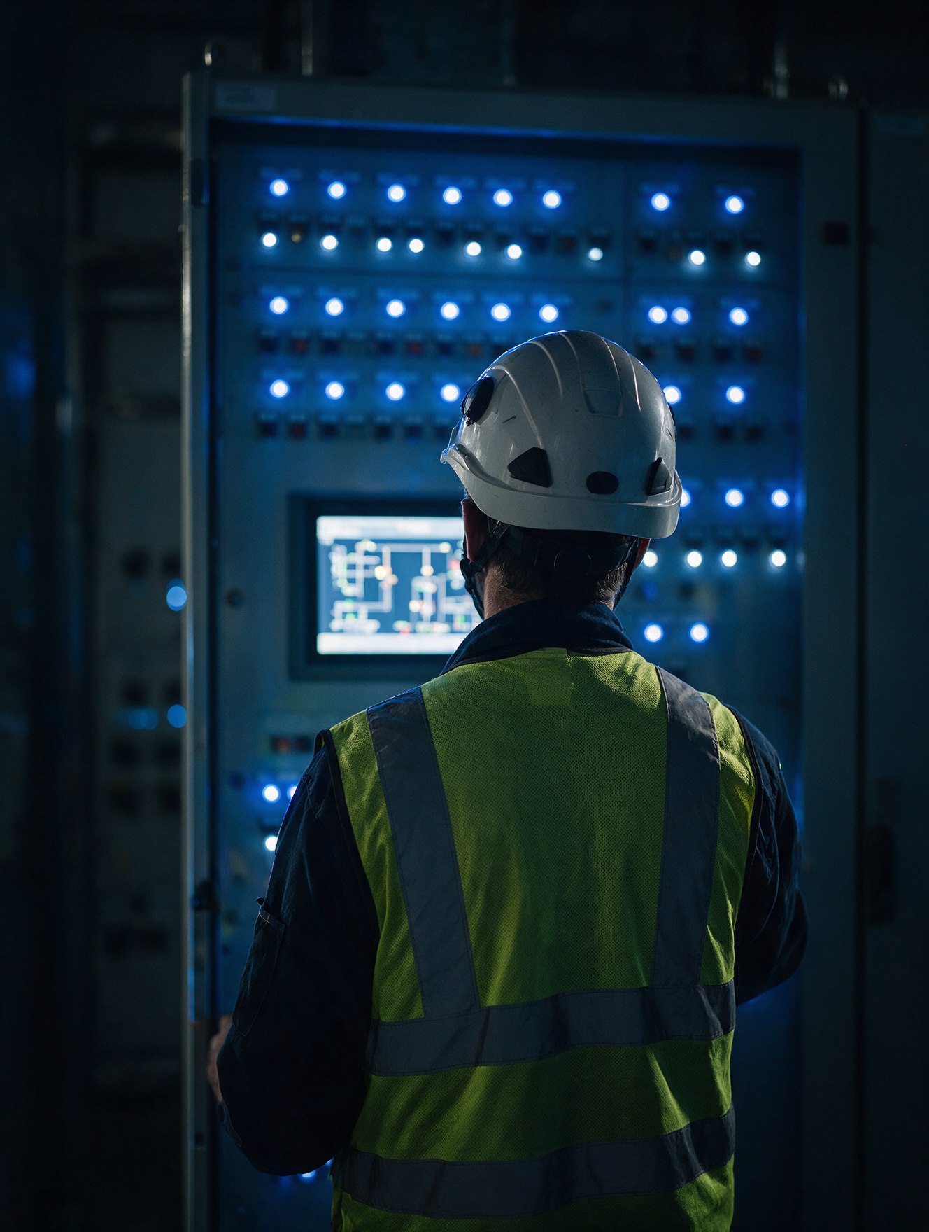 Commissioning technician at an illuminated switchgear control panel